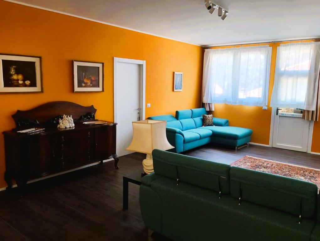 a living room with a blue couch and orange walls at An exclusive NEW apartment designed for modern living with timeless style in Bellano