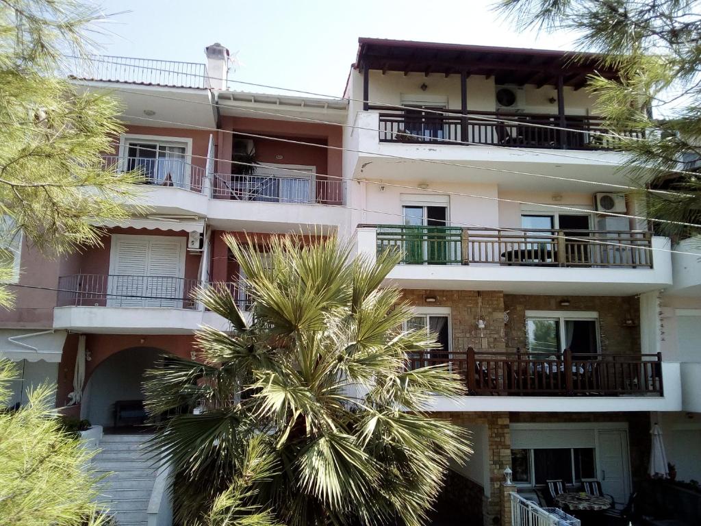 an apartment building with a palm tree in front of it at Blue and Green in Neos Marmaras