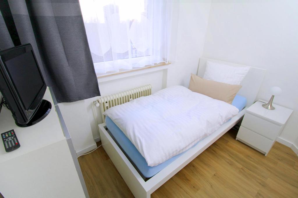 a small white bedroom with a bed and a window at Apartments Sankt Augustin in Sankt Augustin