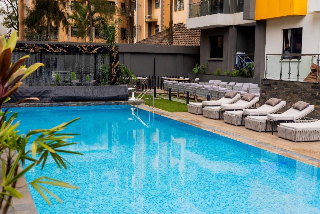 a large swimming pool with lounge chairs next to a building at Pretty haven-studio apartment -Kilimani in Nairobi