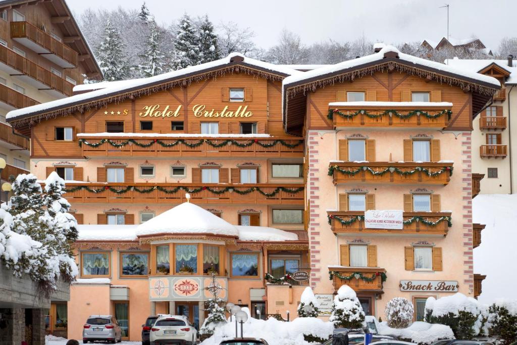 a large building with snow on top of it at Hotel Cristallo in Andalo