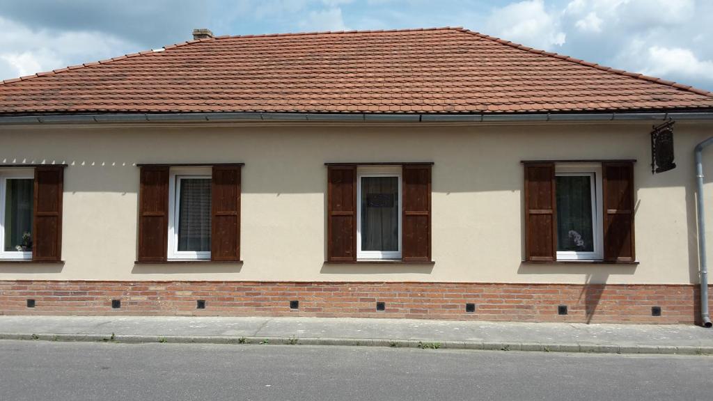 een huis met bruine ramen en een rood dak bij Réka Vendéghàz in Tokaj