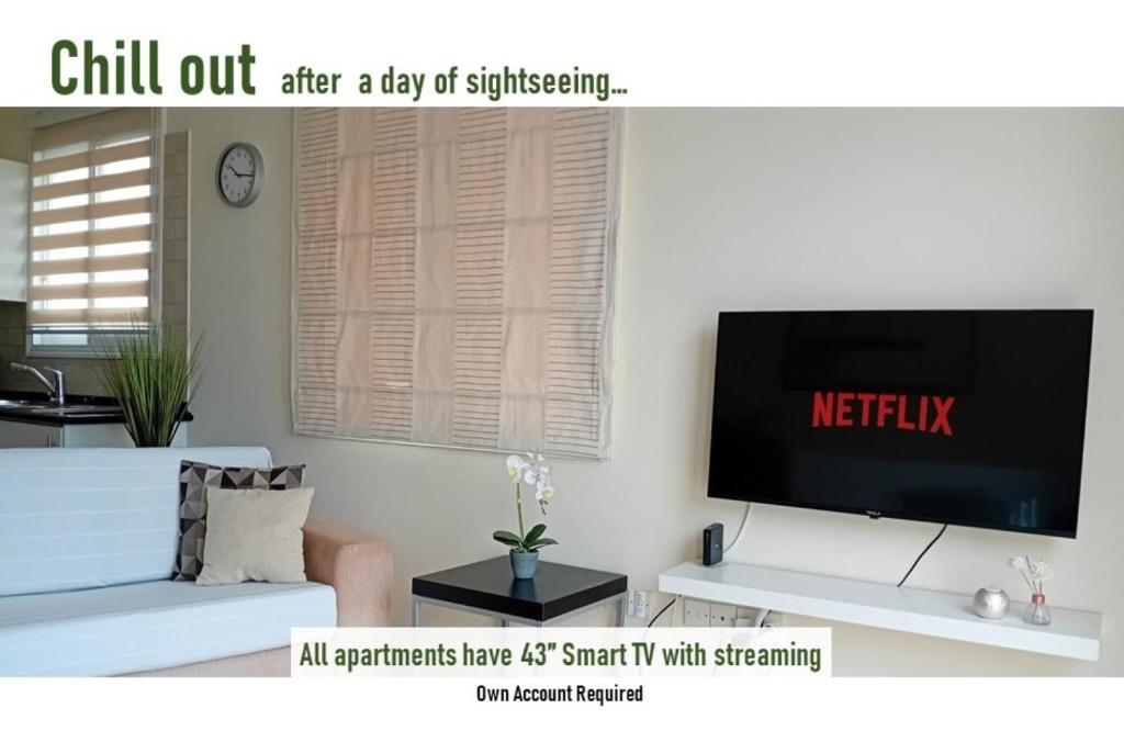 Una sala de estar con televisión y un sofá. en Kato Paphos Suites, en Nea Paphos