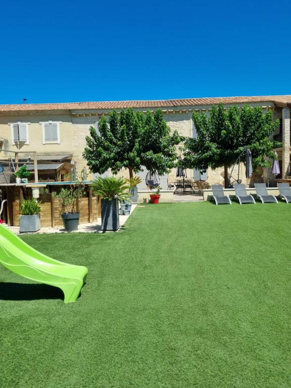 une cour avec un toboggan vert sur l'herbe dans l'établissement Mas provençal, à Mézoargues