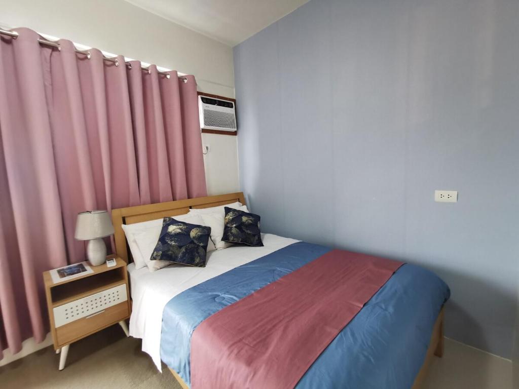 a bedroom with a bed with pink curtains at Coastal Stay at Oceancrest in Cebu City