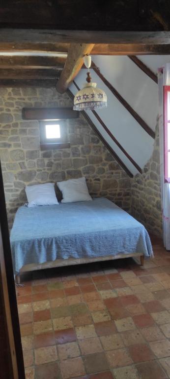 ein Schlafzimmer mit einem Bett in einer Ziegelwand in der Unterkunft Villa rivière sur le Golfe in Pluneret