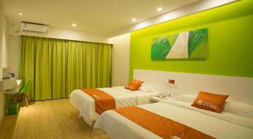 ein Hotelzimmer mit 2 Betten und einer grünen Wand in der Unterkunft Shell Qionghai Jinhai Road Hotel in Qionghai