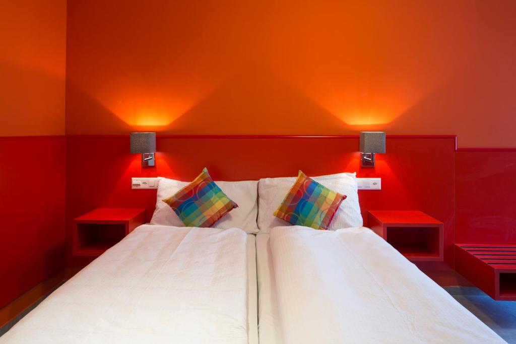 a bedroom with red walls and a bed with two pillows at Hotel Liberty Self Check-In in Bellinzona