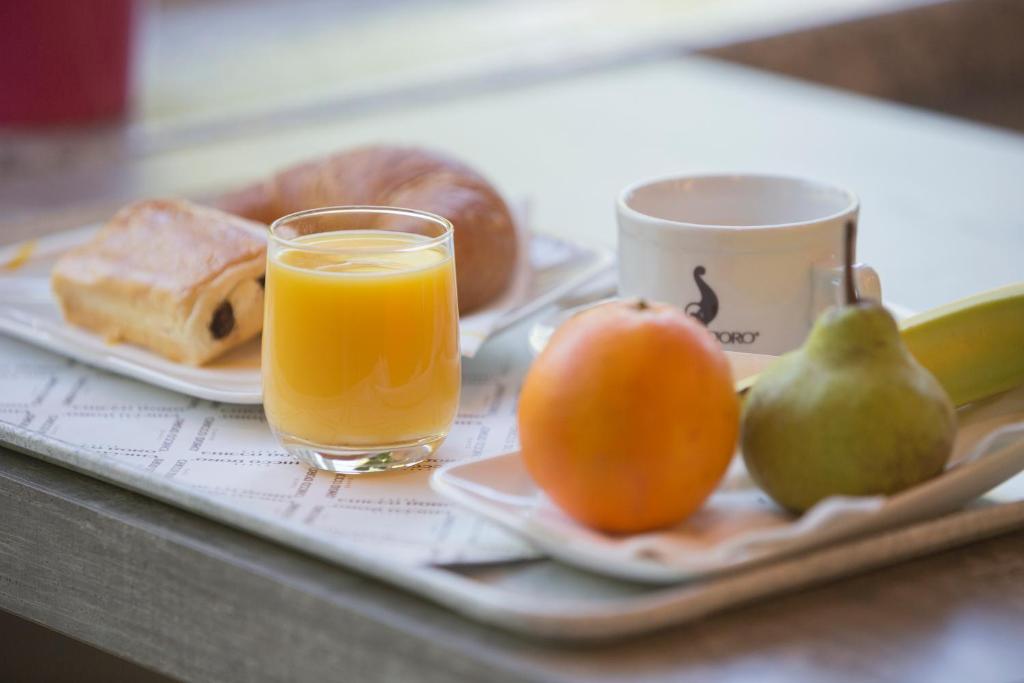 a tray with a plate of fruit and a glass of orange juice at Hotel Liberty Self Check-In in Bellinzona