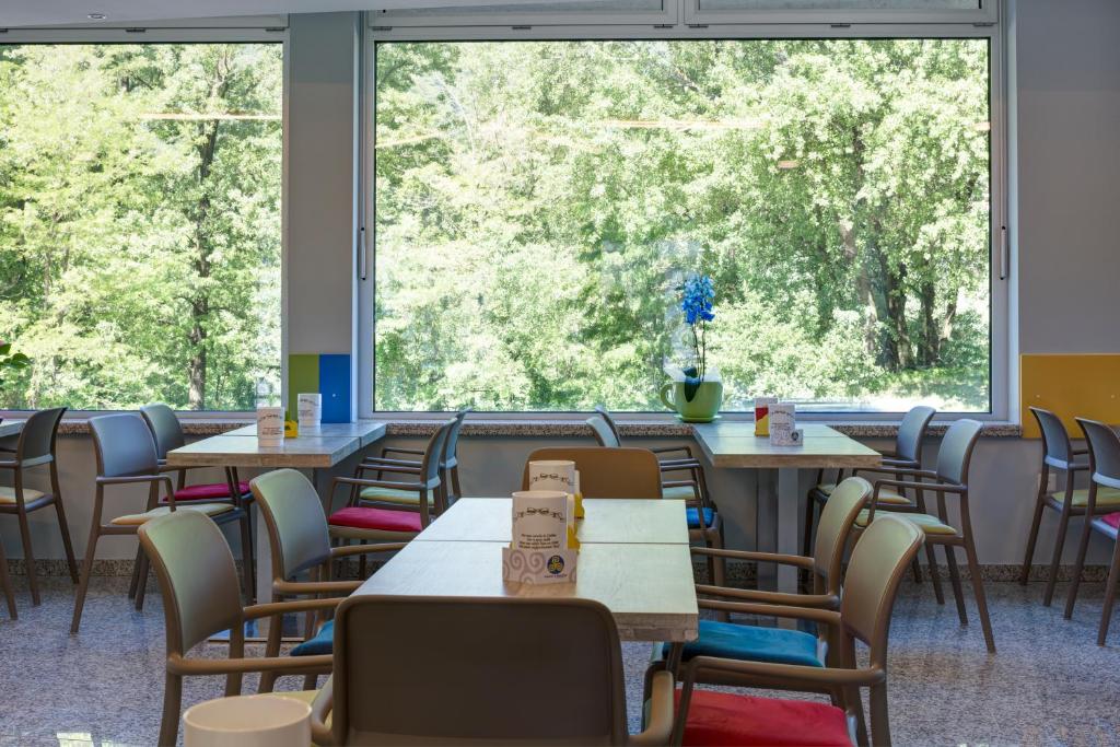 a dining room with tables and chairs and a large window at Hotel Liberty Self Check-In in Bellinzona