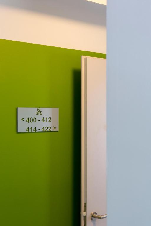 a sign on a green wall next to a door at Hotel Liberty Self Check-In in Bellinzona