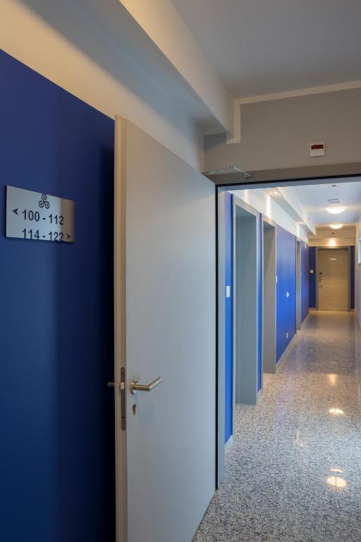 a corridor of an office with blue walls and a door at Hotel Liberty Self Check-In in Bellinzona