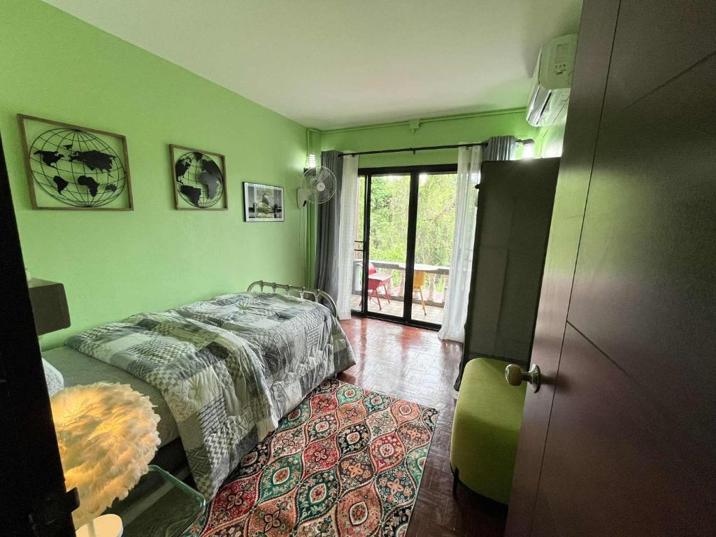 ein Schlafzimmer mit grünen Wänden, einem Bett und einem Teppich in der Unterkunft Wiang Ping house in Chiang Mai