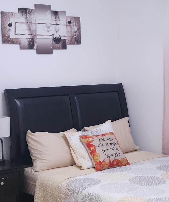 a bed with a black headboard and some pillows at Abby's Comfort in North Woodmere