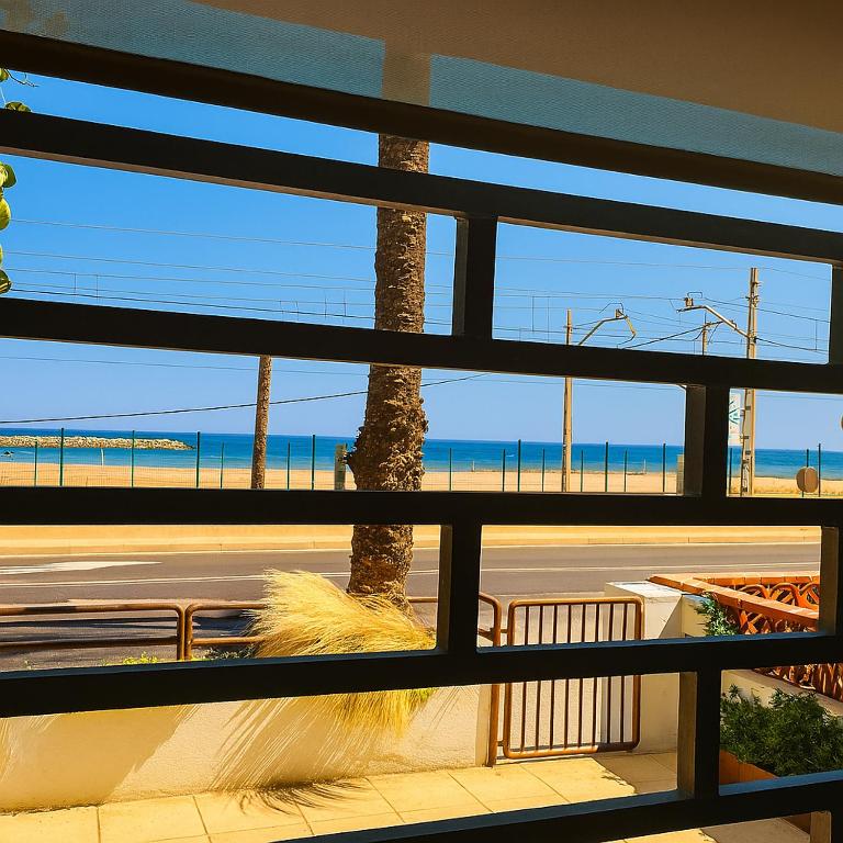 a view of a beach from a window with a palm tree at La Bellamar - Apartamento en primera línea mar- in Premiá de Mar