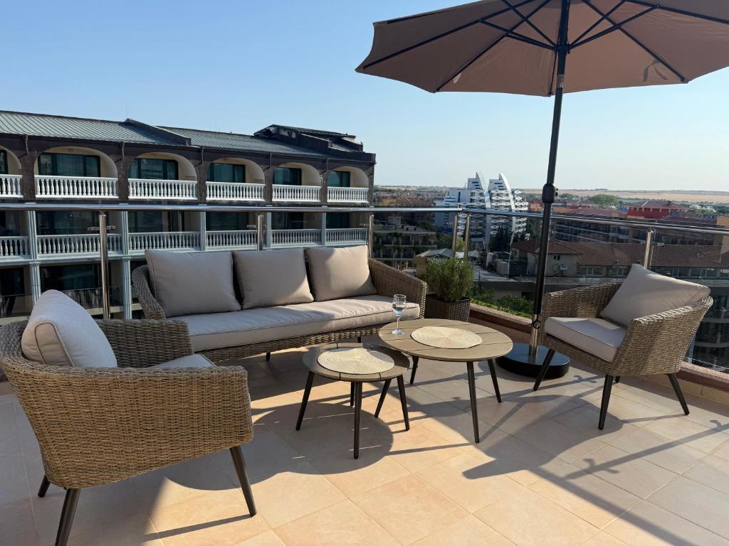 a patio with a couch and tables and an umbrella at Admiral Plaza Apartments in Sunny Beach