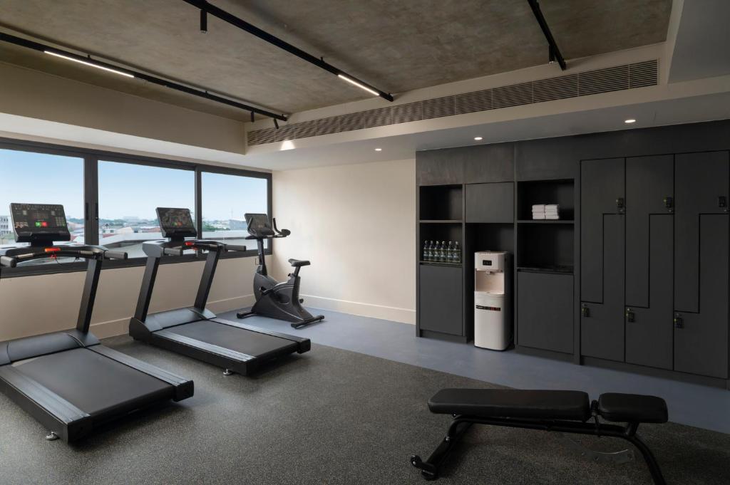 A windowed fitness room with treadmills, a bike, bench and storage lockers.
