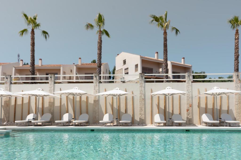 a pool with chairs and umbrellas and palm trees at Helios Blue Villas Kriopigi Kassandra in Kriopigi