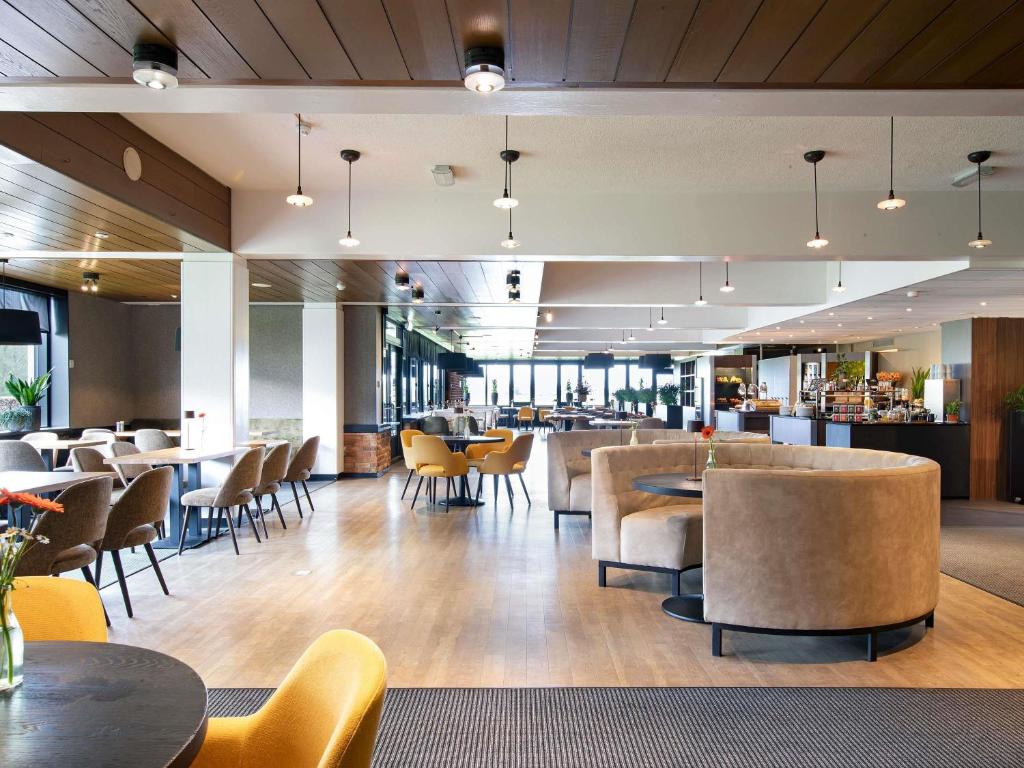 a restaurant with tables and chairs and a bar at Mercure Hotel Zwolle in Zwolle