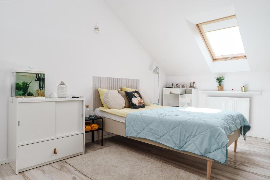 a white bedroom with a bed and a window at Cozy Attic in Marki