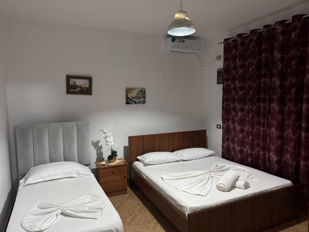 twee bedden in een hotelkamer met witte lakens bij Elmir apartament's in Ksamil