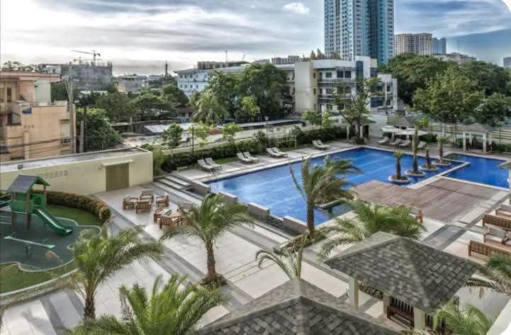 a large swimming pool with palm trees in a city at LaVerti 1BR Affordable staycation groups family in Manila