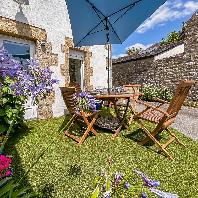 a table and chairs and an umbrella on a lawn at Cocon Familial Surf & Menhirs Idéal Golfe Morbihan in Plouharnel