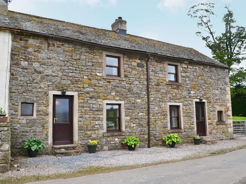 a stone house with potted plants in front of it at Swaledale Cottag in Caldbeck