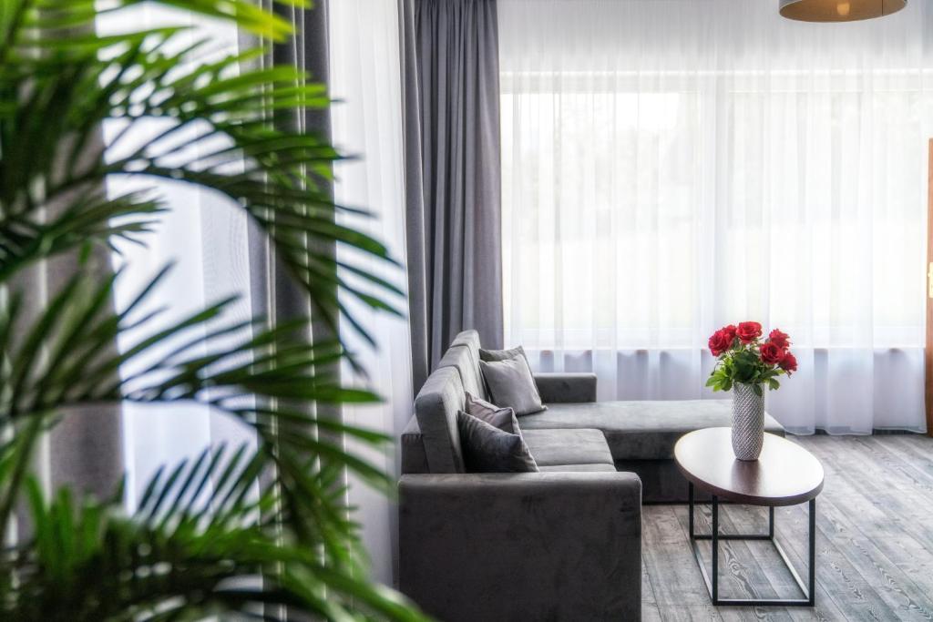a living room with a couch and a table with flowers at Sądelski Resort Apartments in Zakopane