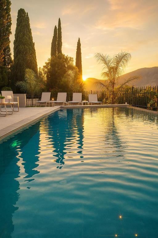 a swimming pool with chairs and a sunset in the background at Villa Harmony Luxury Resort in Corfu