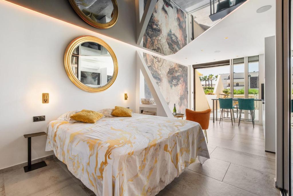 a bedroom with a bed and two mirrors on the wall at AmbassadOr Elegance and comfort steps from the naturist beach in Cap d'Agde