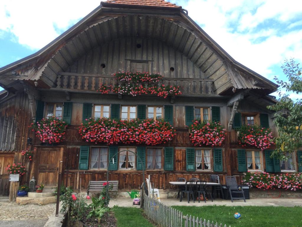 een groot houten huis met bloemen in de ramen bij Appartement La Croix in Villarvolard