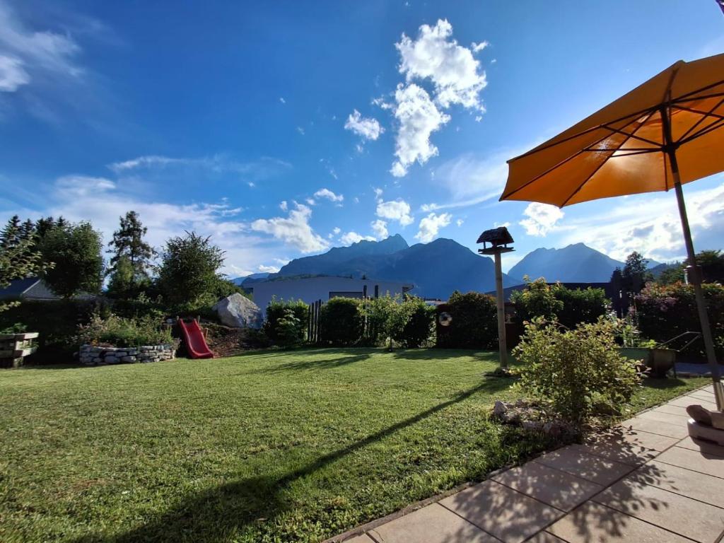 a lawn with an umbrella and mountains in the background at Ferienwohnung Zimmerle in Pflach