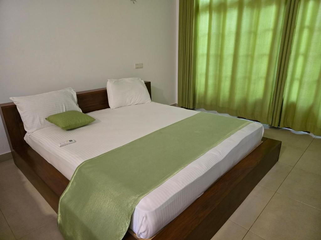 a bedroom with a large bed with a green curtain at Hotel Serugahawatta in Wellawaya