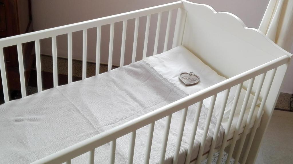 Białe łóżeczko z zegarem na nim w obiekcie Sweet Home w mieście Faggeto Lario 