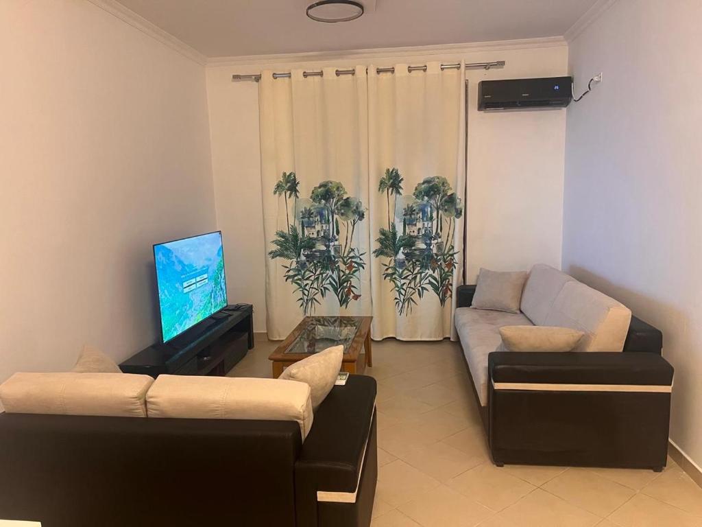 a living room with two couches and a flat screen tv at Entire Apartment near Air Albania in Tirane