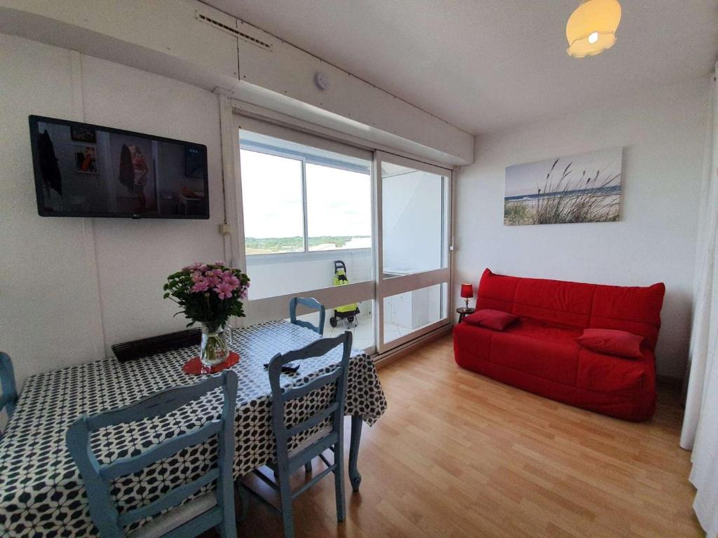 un salon avec un canapé rouge et une table dans l'établissement Studio cosy à 50m de la plage - 4 couchages, loggia vue mer, lave-linge, ménage inclus - FR-1-224C-418, à Saint-Hilaire-de-Riez