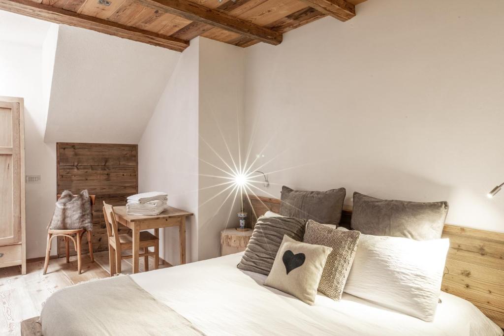 a bedroom with a white bed and a table at Mountain Dolomiti Apartments-Maison Perrod in Predazzo