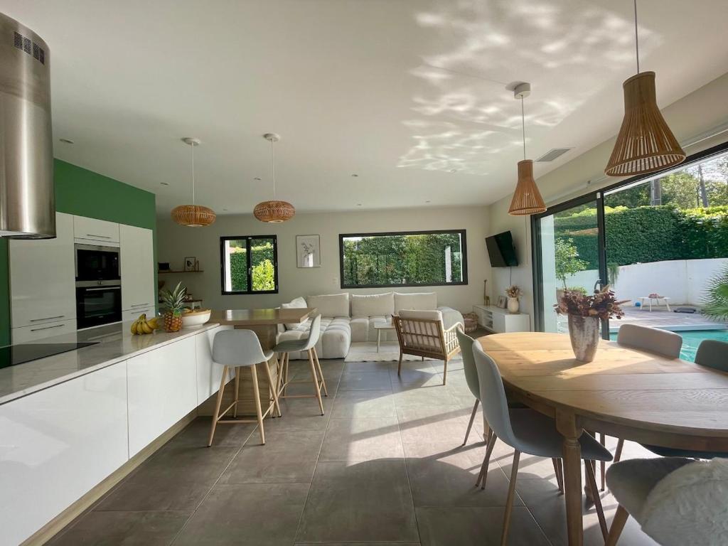 a kitchen and living room with a wooden table and chairs at Maison individuelle contemporaine avec piscine in Urrugne