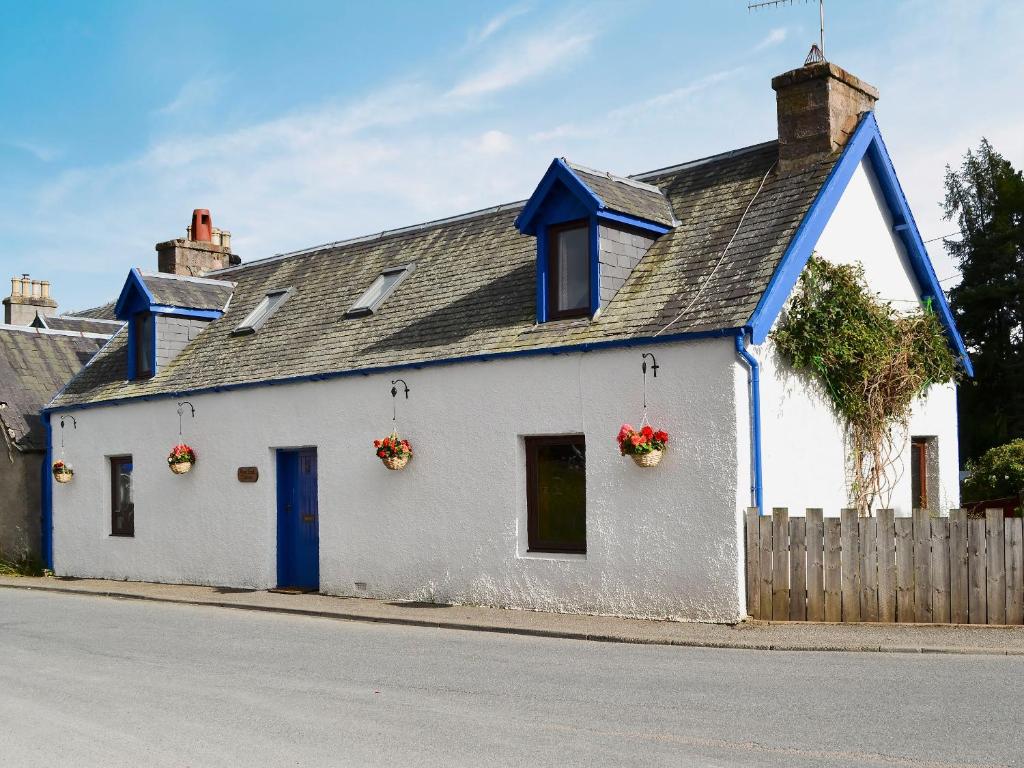 una casa bianca con finiture blu su una strada di West End Cottage a Carrbridge