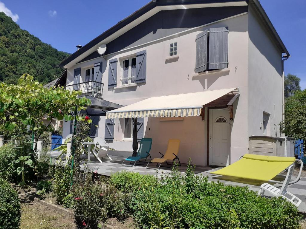 une maison avec un patio avec des chaises et un auvent dans l'établissement le lys dans la vallée d ustou, à Ustou