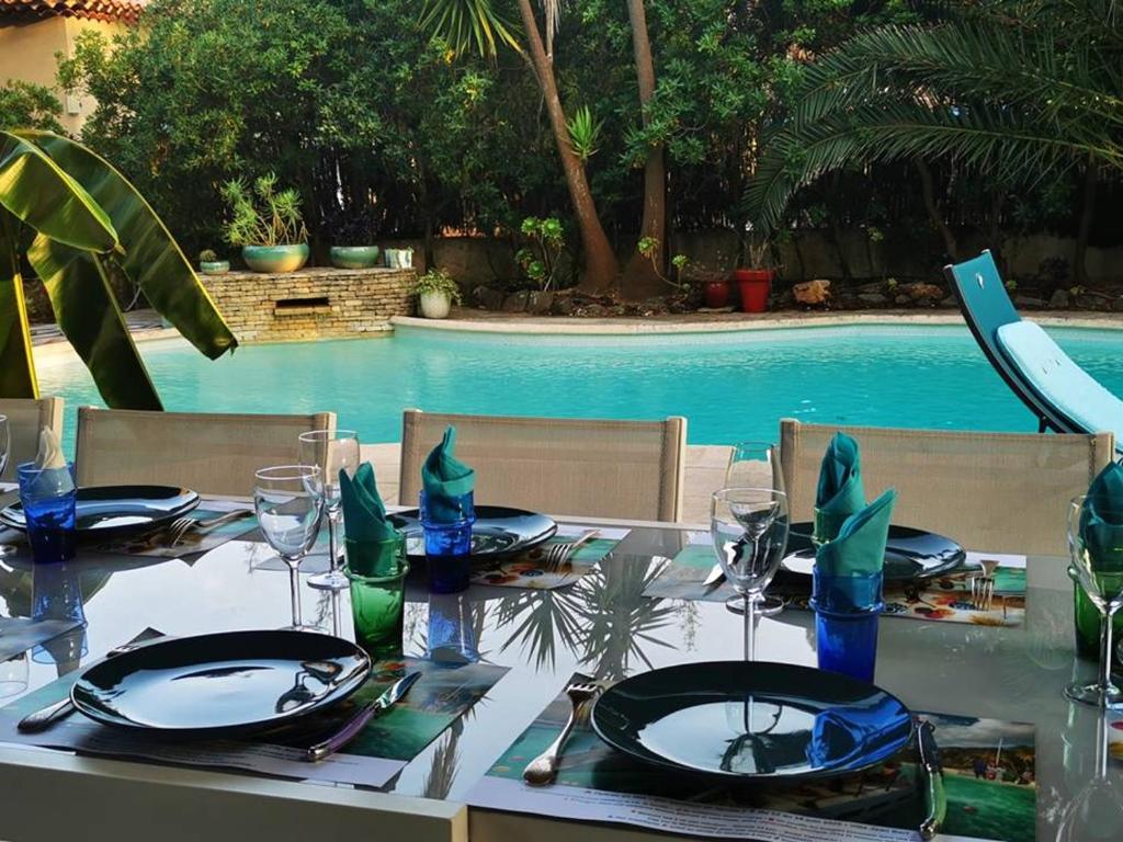 - une table pour un repas en face de la piscine dans l'établissement Villa à Hyères avec piscine, climatisation et Wi-Fi, à 5 min de la plage - FR-1-335-169, à Hyères