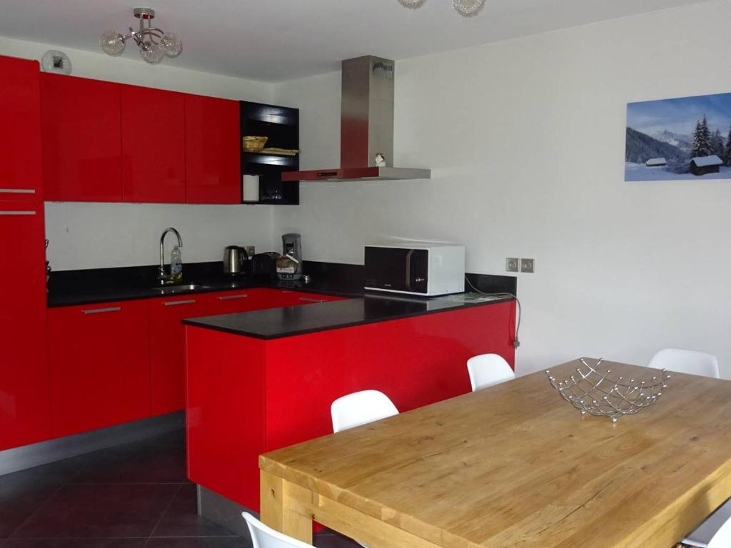 une cuisine avec des placards rouges et une table en bois dans l'établissement Appartement lumineux aux Gets, 3 pièces, garage, confort, 5 pers, WiFi, proche pistes - FR-1-802-32, aux Gets