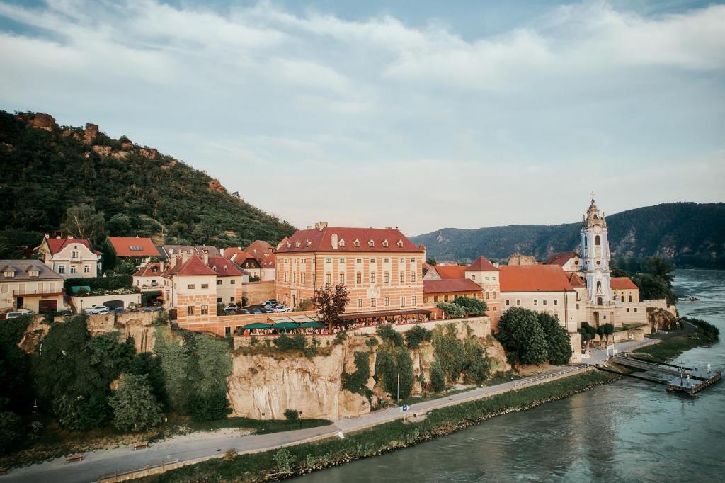 a town on a hill next to a river at Hotel Schloss Dürnstein in Dürnstein