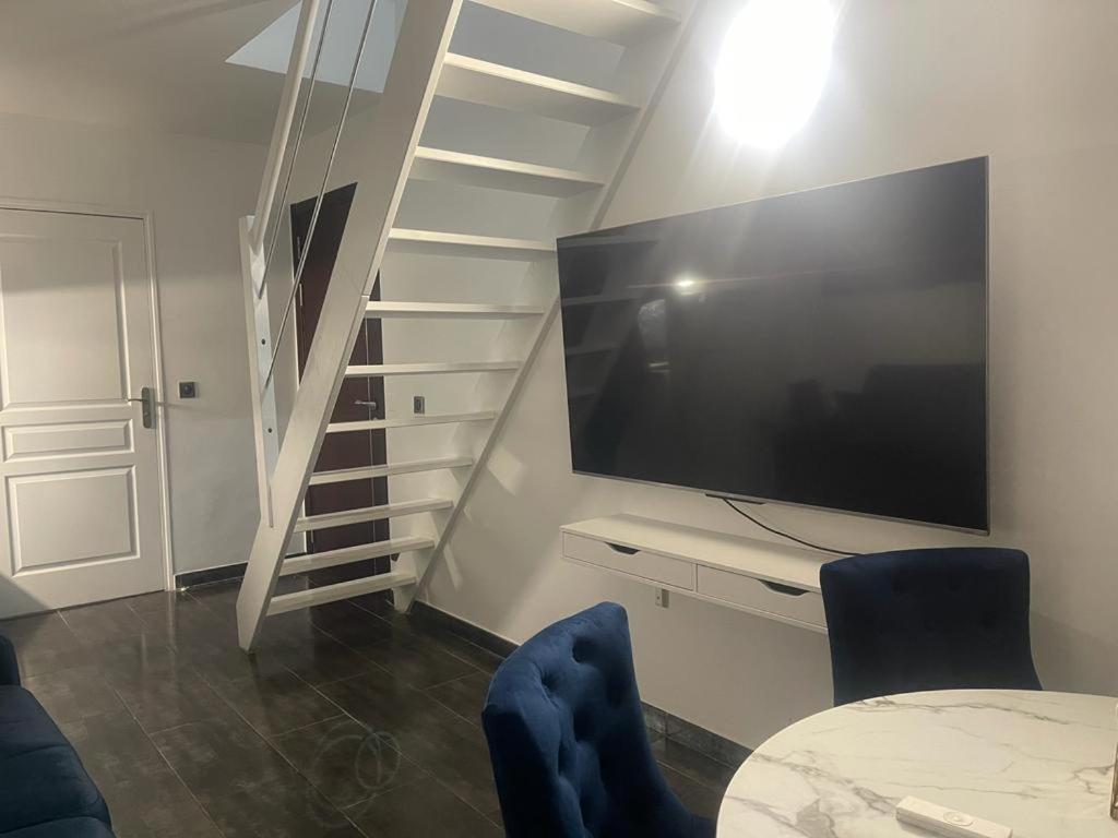 sala de estar con TV y escalera en Pleasant Duplex, en Neuilly-sur-Marne