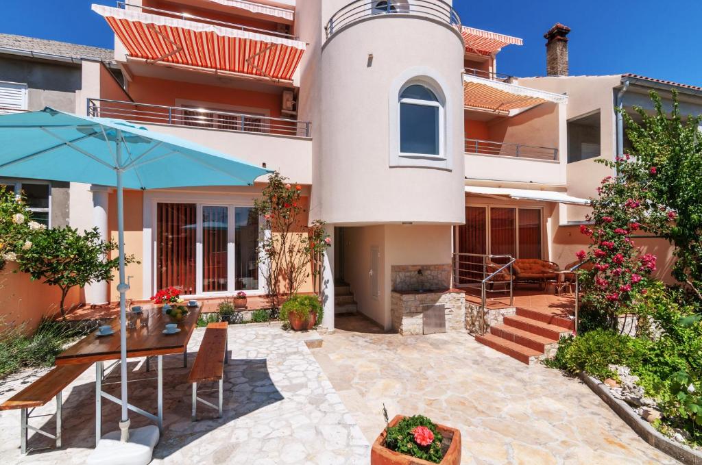 una casa con patio con tavolo e ombrellone di Apartments Jadranka a Privlaka (Brevilacqua)