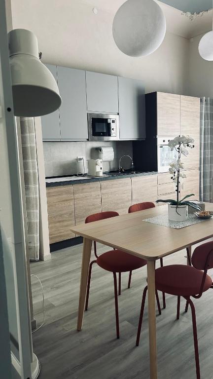 a kitchen with a wooden table and red chairs at Civico 18 Guest House in Cuneo