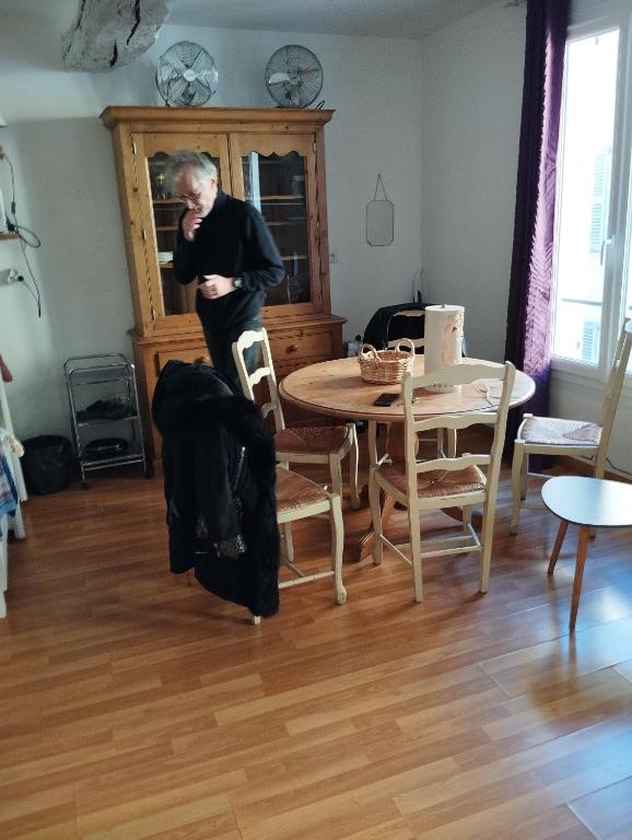 a man standing in a living room with a table at Appartement d'Artiste in Cotignac