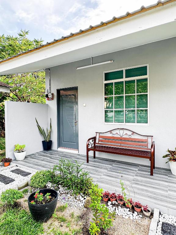 a bench on a wooden deck in front of a house at NAR Kampung Studio in Bayan Lepas