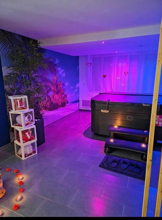 Cette chambre dispose d'une baignoire avec des lumières violettes et roses. dans l'établissement L'escale du désir, Spa privatif, à Calais